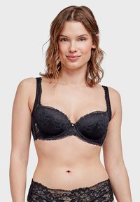 Soutien-gorge en dentelle noire avec soutien en sous-vêtement, motifs floraux délicats, bretelles réglables et un petit accent décoratif en or au centre.