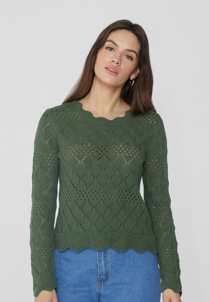 Grüner gestrickter Pullover mit einem design im Diamantmuster, langen Ärmeln und einem gewellten Saum. Leichte Textur mit offenen Webarten.