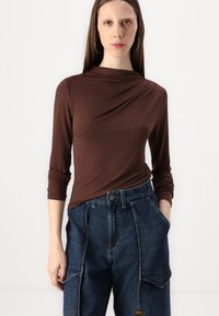 Krus hihna t-shirt ala dangenja, koji je u paru sa plavim trapericama cargo sa bočnim džepovima i vidljivim detaljima šivanja.