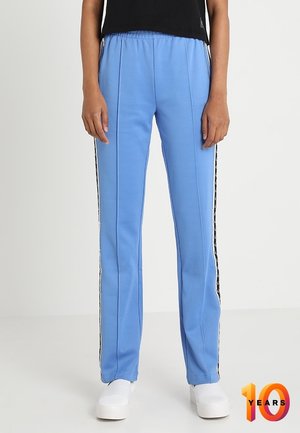 Vaaleansiniset urheiluhousut, joissa on joustava vyötärö, mustat sivuviivat ja suora leikkaus. Valmistettu sileästä, joustavasta materiaalista.