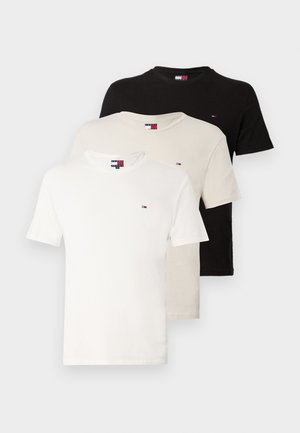Trois t-shirts en coton de couleur blanche, crème et noire, chacun avec un col rond et un petit logo sur la poitrine. Texture lisse, manches courtes.