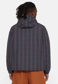 Giacca a quadri navy con cappuccio, caratterizzata da linee verticali e orizzontali in rosso e bianco, polsini elasticizzati e una vestibilità comoda.