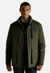 Ciemnozielona kurtka z wysokim kołnierzem, wieloma przednimi kieszeniami i zapięciem na zamek. Tkanina wydaje się teksturowana i lekko błyszcząca.