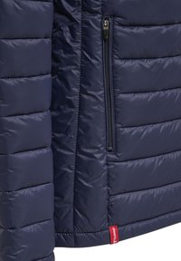 Giacca imbottita blu navy con design a trapunte orizzontali, dotata di una tasca con zip e un'etichetta rossa del marchio sull'orlo. Tessuto liscio e lucido.