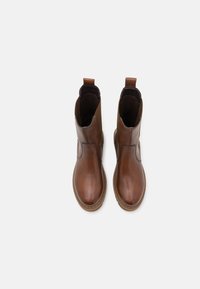 Brązowe skórzane botki za kostkę z gładkim wykończeniem, elastycznymi panelami bocznymi i uchwytami dla łatwego zakładania. Solidny, okrągły czubek i płaska podeszwa.