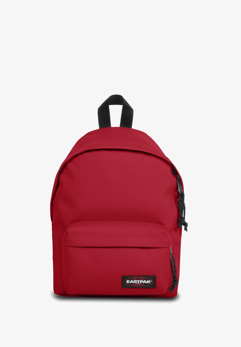 Mochila Eastpak roja con tejido suave, forma redondeada, bolsillo frontal con cremallera y correas negras. Presenta un parche con el logo en la parte frontal.