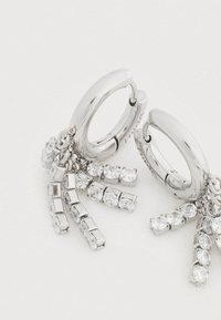 Ατσάλινα σκουλαρίκια σε σχήμα κρίκου με κρεμαστά κρύσταλλα. Διαθέτουν μια ποικιλία από στρογγυλά και ορθογώνια πετράδια συνδεδεμένα με λεπτές αλυσίδες.