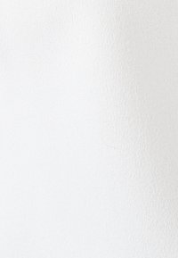 Tessuto bianco con una superficie testurizzata, che mostra un fine motivo intrecciato e una leggera lucentezza. Il materiale appare liscio e uniforme in tutto.