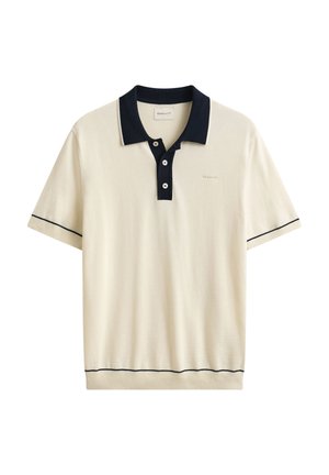 Cremfarbenes kurzärmeliges Poloshirt mit marineblauem Kragen, Dreiknopfleiste, marineblauem Besatz an Ärmeln und Saum sowie dezentem Logo auf der Brust.