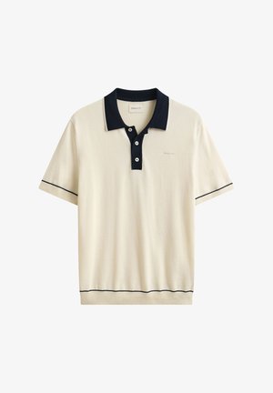 Cremfarbenes kurzärmeliges Poloshirt mit marineblauem Kragen, Dreiknopfleiste, marineblauem Besatz an Ärmeln und Saum sowie dezentem Logo auf der Brust.