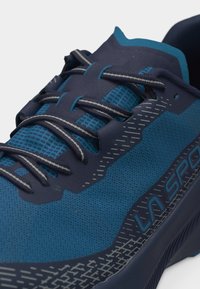 Zapatilla deportiva azul con cordones oscuros, parte superior de malla transpirable y borde de la suela con diseño que muestra la marca La Sportiva.