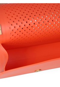 Oranje geperforeerde handtas met stervormige uitsparingen, een gladde textuur en een sluiting met een goudkleurige drukknoop. De binnenkant is ongelijk en ruim.