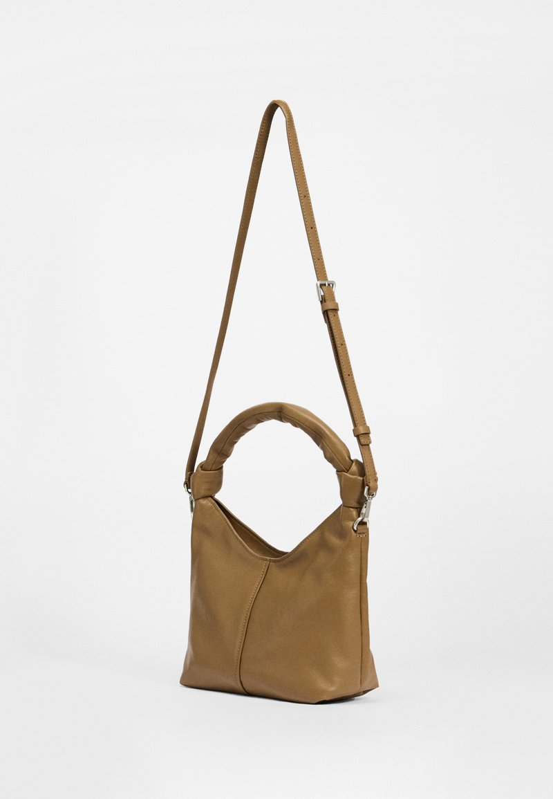 Braune Lederhandtasche mit einem geschwungenen Griff, verstellbarem Riemen und dezenten Nahtdetails. Weiche Textur und minimalistisches Design.