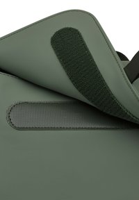 Groene tas met een gladde, matte buitenkant; heeft een gestructureerde grijze stofstrip en klittenbandsluiting; minimalistisch ontwerp zonder patronen.