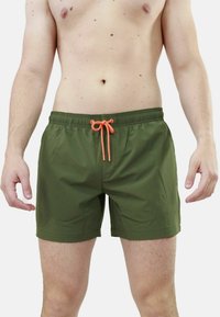 Pantaloni da bagno verdi con elastico in vita e cordino arancione. Tessuto liscio con lunghezza fino alla metà della coscia e senza motivi o accessori visibili.