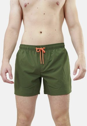 Pantaloni da bagno verdi con elastico in vita e cordino arancione. Tessuto liscio con lunghezza fino alla metà della coscia e senza motivi o accessori visibili.