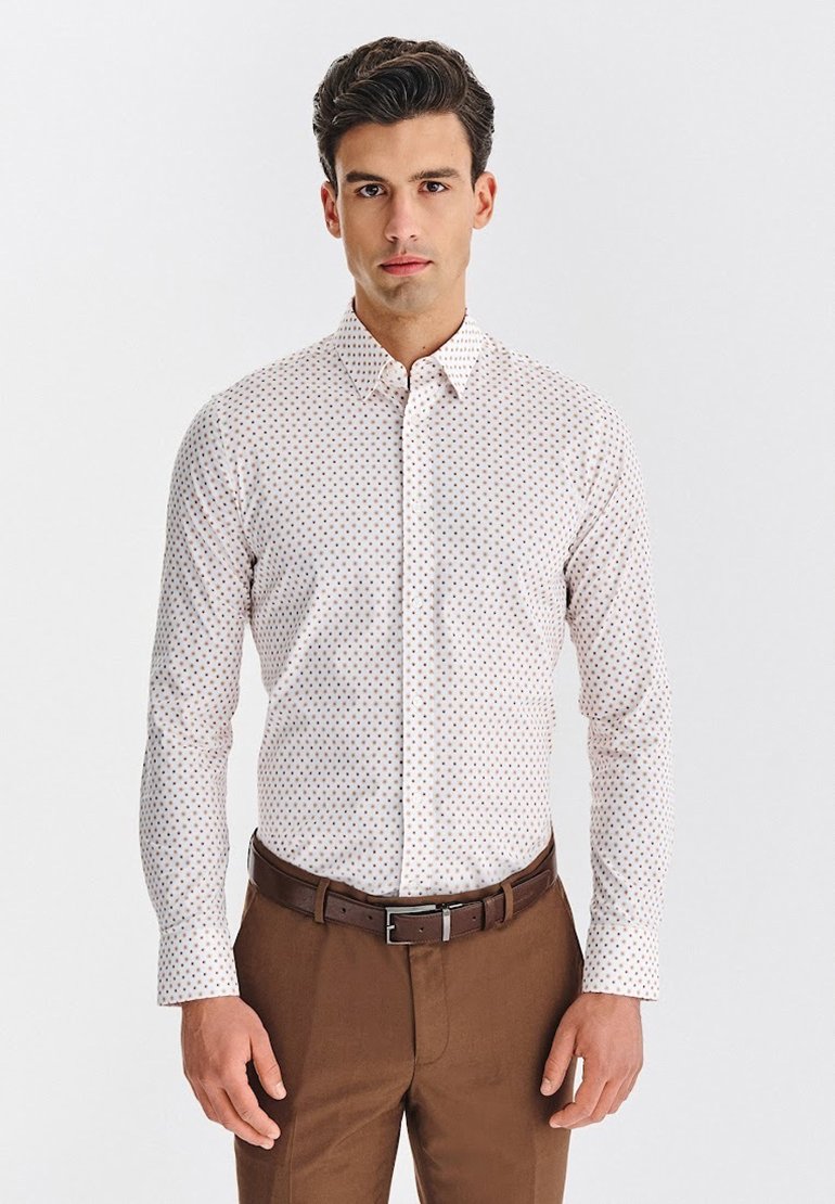 Biała koszula z długim rękawem w mały, kolorowy wzór w kropki. Połączona z brązowymi spodniami i pasującym paskiem. Gładka tekstura.