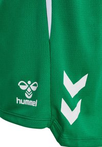 Shorts de sport verts avec logo d'abeille hummel blanc et deux chevrons blancs sur un tissu léger et texturé.