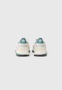 Witte en turquoise Adidas sneakers met een gelaagd ontwerp, voorzien van een gestructureerde bovenkant, reflecterende accenten en een dikke rubberen zool.