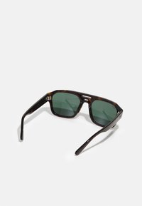 Ochelari de soare tortoise-shell cu lentile verzi, design unghiular, rame groase și accente metalice pe brate. Brațe texturate pentru aderență.