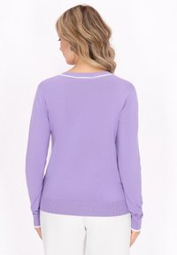 Ljuslila långärmad tröja, ribbad textur, vit krageaccent, figursydd design, sedd bakifrån.