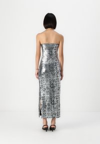 Sudrabota čūska-izdrukas strapless kleita ar pieguļošu augšdaļu un augsto šķēlumu, ar gludu tekstūru un elegantu dizainu.