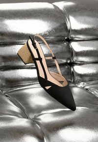 Must musta erilise nuiaga slingback kingad lõikega detailidega, tekstuuriga paelapealne kanna, beige siseruumiga, esitatud metallik hõbedasel pinnal.