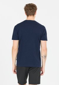 Marinblå t-shirt med kort ärm i bomull, med rund halsringning och avslappnad passform, tillsammans med svarta träningsshorts.