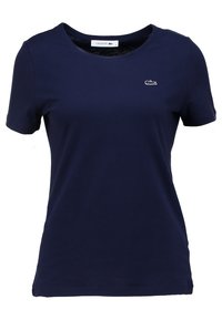 Námořnická modrá bavlněná tričko s kulatým výstřihem, krátkými rukávy a vyšitým logem Lacoste na levé straně hrudi. Hladký povrch.