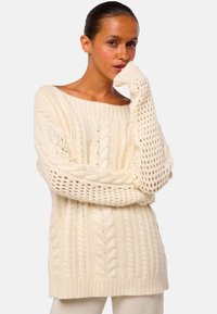 Chunky Creme-Pullover mit lockerer Passform, ausgestattet mit Kabelstrickdesign, offenen Ärmel und geripptem Saum. Weiche Textur, gemütliches Erscheinungsbild.