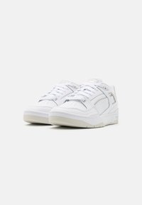 Hvide sneakers med en tekstureret læderoverdel, polstret tunge og en gummisål. Udstyret med stitch-detaljer og et diskret logo på siden.