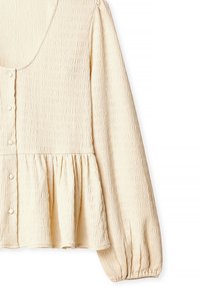 Kremo spalvos bliuska, pagaminta iš tekstūruotos medžiagos, su apvaliame kakle iškirpte, mygtukų uždarymu ir susiraukšlėtu liemeniu, turinti ilgas pūstines rankoves.