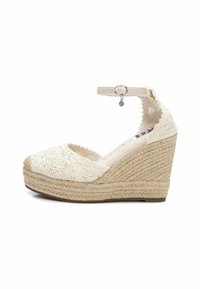 Alpargatas de cuña beige con parte superior texturizada y correa en el tobillo. Detalles de cuerda en la cuña y puntera redonda, adornadas con patrones decorativos.