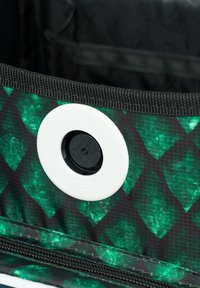 Zielona tkanina w wzór w diamenty, z białym okrągłym zapięciem i czarnym zamkiem błyskawicznym, wewnątrz torby lub etui.