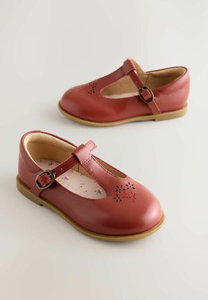 Červené kožené topánky Mary Jane so zaoblenou špičkou, bočnou prackou, vystihanými detailmi a stielkou s kvetinovým vzorom na hnedej gumenej podrážke.