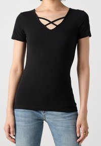 Camiseta negra de manga corta con escote en V y diseño entrecruzado en el cuello, hecha de un material suave y elástico, con silueta ajustada.
