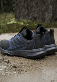 Czarne i ciemnoniebieskie buty sportowe z teksturowanej tkaniny, wzmocnionymi czubkami oraz gumowymi podeszwami. Posiadają wzmocnione pętle na pięcie, co ułatwia zakładanie.