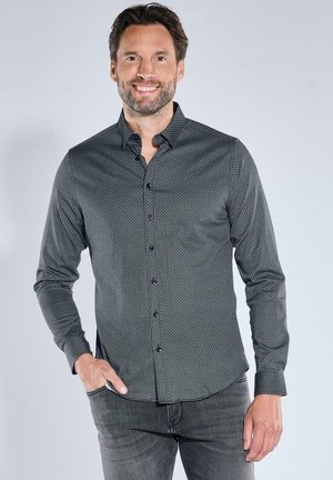 Dark gray button-up shirt featuring a subtle geometric pattern, long sleeves, and a classic collar, paired with gray jeans.