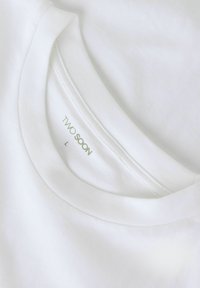 Hvid bomuld T-shirt med ribstrikket rund hals. Label indeni med teksten "TWO SOON" og størrelse "L" trykt under. Glat tekstur.