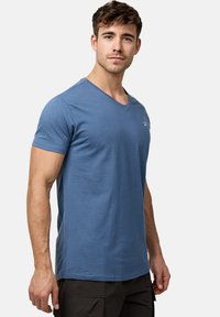 Blå v-hals t-shirt lavet af blød bomuldsblanding. Korte ærmer, tætsiddende design og diskret logo på brystet. Glat tekstur, afslappet stil.