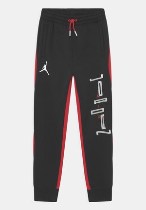Joggeurs athlétiques noirs et rouges avec taille élastique, cordon rouge, poches latérales, logo Jumpman blanc et texte vertical « Jordan » sur la jambe droite.