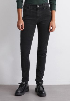 Černé kordové skinny džíny s předními kapsami, vysokým pasem a mírným elastanem. Sestavené s černými šněrovacími kotníkovými botami.