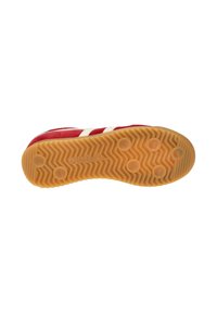 Suela de zapatilla roja con una base de goma texturizada, que presenta agarres hexagonales y un patrón ondulado. Rayas blancas a lo largo del costado.