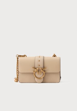 Borsa a mano in pelle beige con un accento circolare dorato che presenta due uccelli. Include una tracolla a catena e un dettaglio di chiusura con borchie.