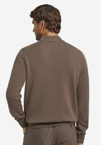 Brązowy sweter z dzianiny z wysokim kołnierzem, ściągaczami na rękawach i u dołu, wykonany z fakturowanej tkaniny. Prosty krój, bez wzorów ani ozdób.