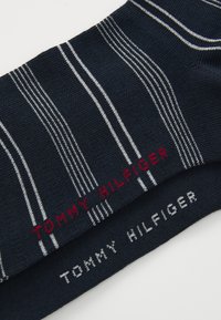 Marineblaue Socken mit weißen und grauen Streifen, versehen mit rotem "TOMMY HILFIGER"-Logo. Weiches Strickmaterial, glatte Textur und elastischer Sitz.