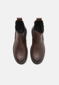 Un par de botines de cuero marrón oscuro pulido con paneles laterales elásticos y tiradores, vistos desde arriba sobre un fondo blanco.