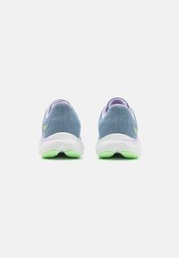 Niebieskie dziewiarskie sneakersy z lawendową i zieloną podeszwą, zaokrąglony kształt, fakturowany materiał i akcent z logo na pięcie.