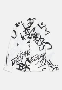 Fehér, hosszú ujjú ing fekete graffiti-stílusú felirattal és absztrakt mintázattal, klasszikus gallérral és egy kis logóval a mellkason.