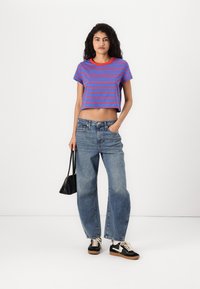 Kuttet blå og rødstripet t-skjorte, høy midje lyse jeans, svarte joggesko og en liten svart veske. Enkel og avslappet antrekk.